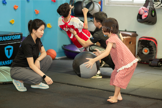 Coaches guiding children during a ball activity in a Vietnam center