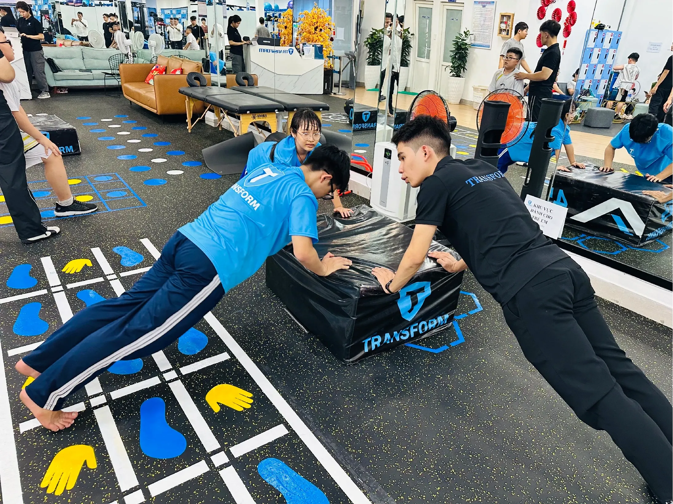 A Transform Kid coach guiding a child through an incline push-up at a Vietnam center